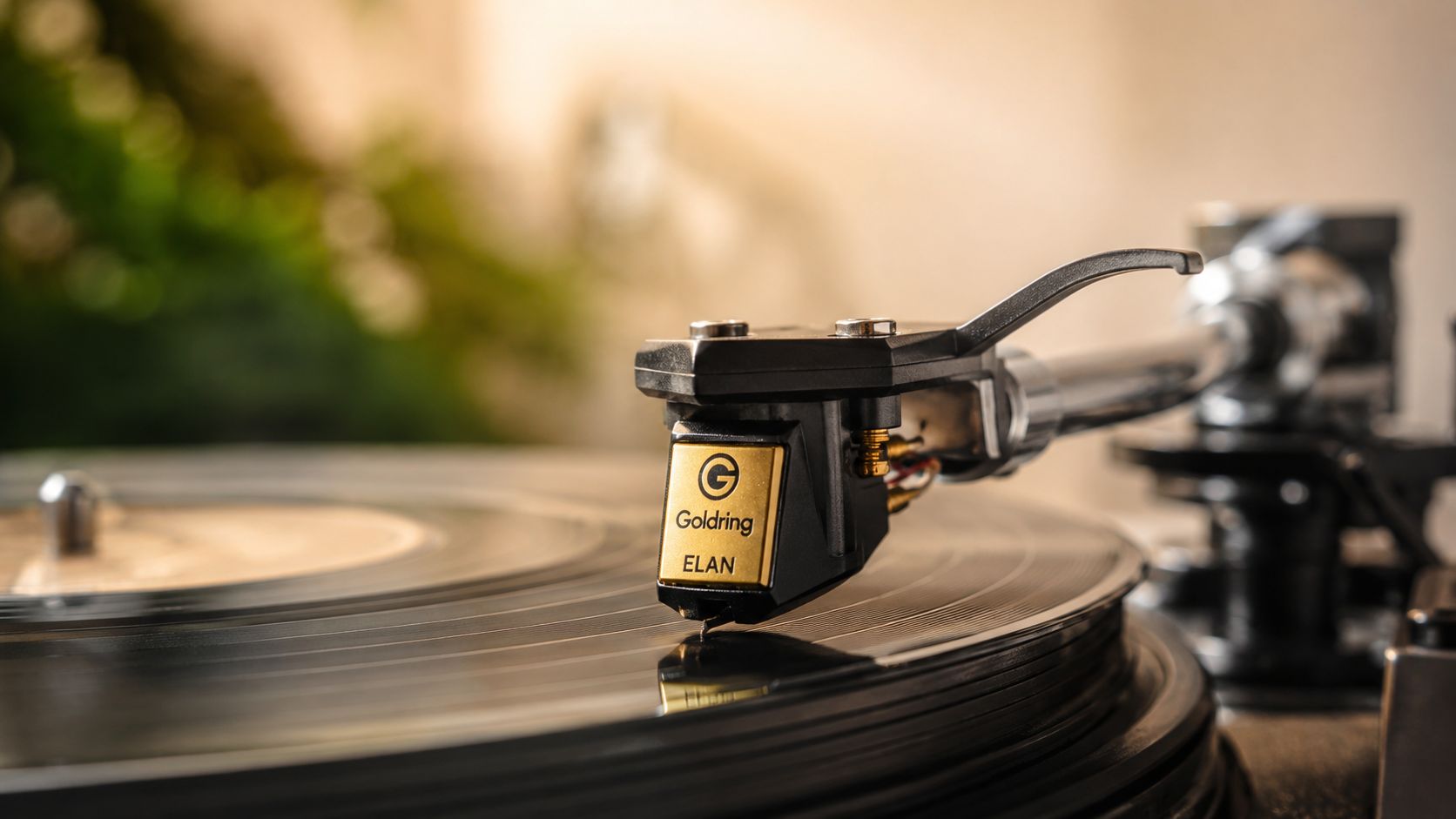A close up view of a Goldring Elan phono cartridge resting on a spinning vinyl record.