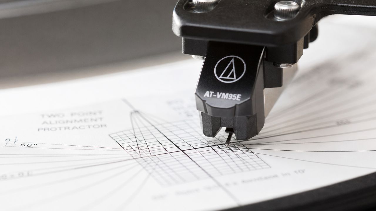 A close-up view of an Audio-Technica turntable cartridge being calibrated on a two-point alignment protractor tool.