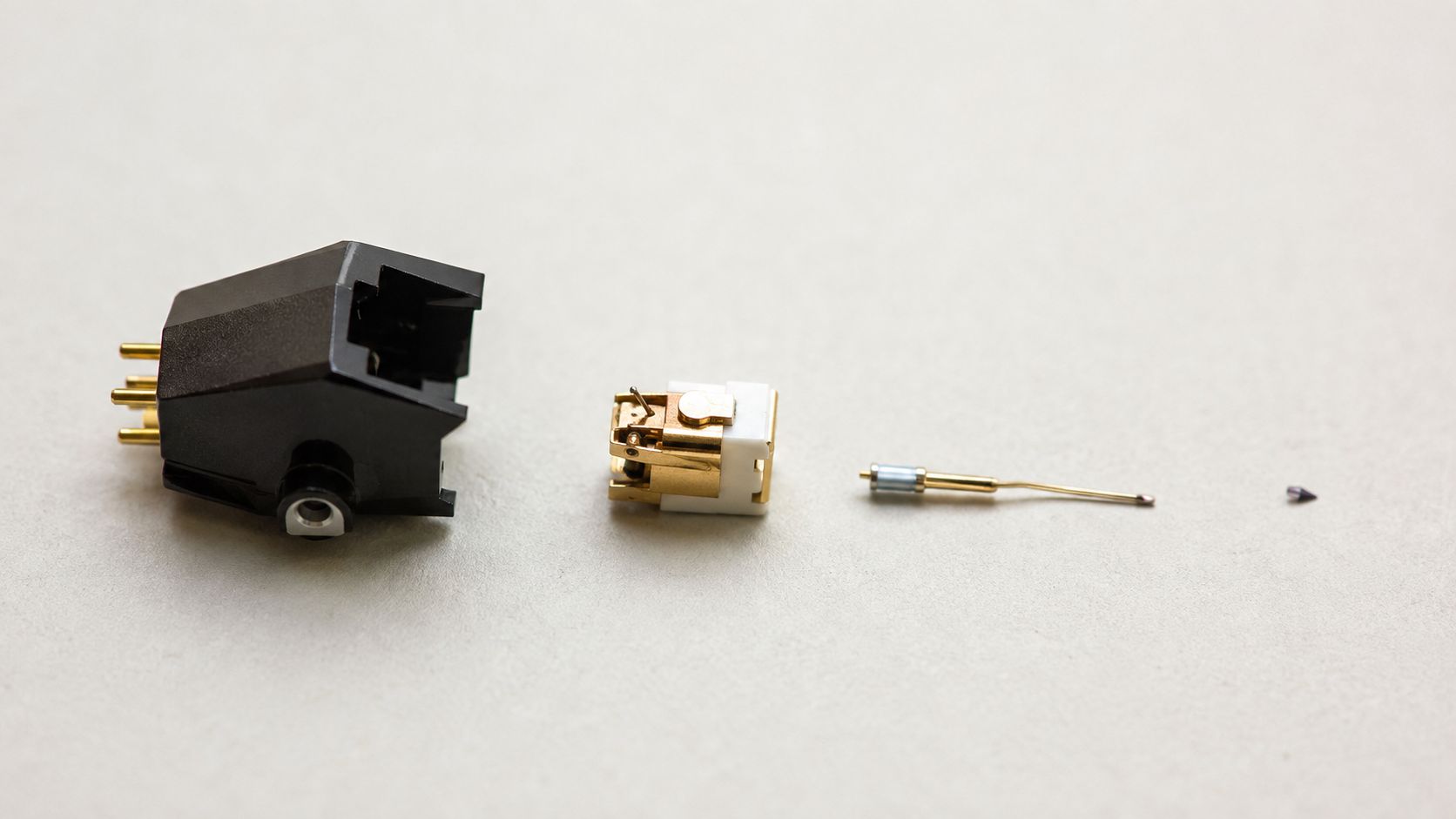 An exploded view of a turntable cartridge showing its main body, internal mechanism, cantilever, and diamond stylus.