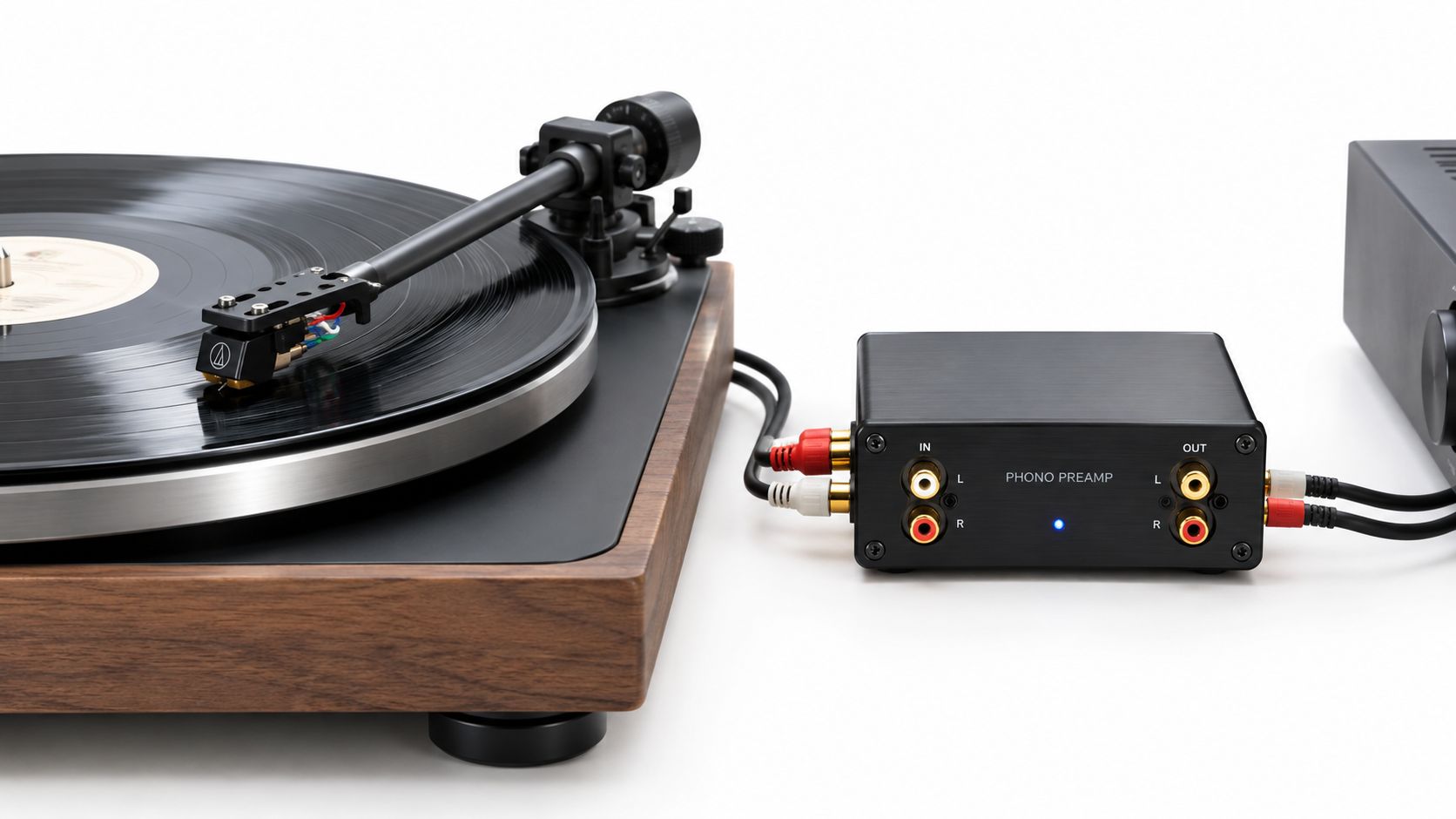 A modern turntable connected to a compact black phono preamp on a clean white background.