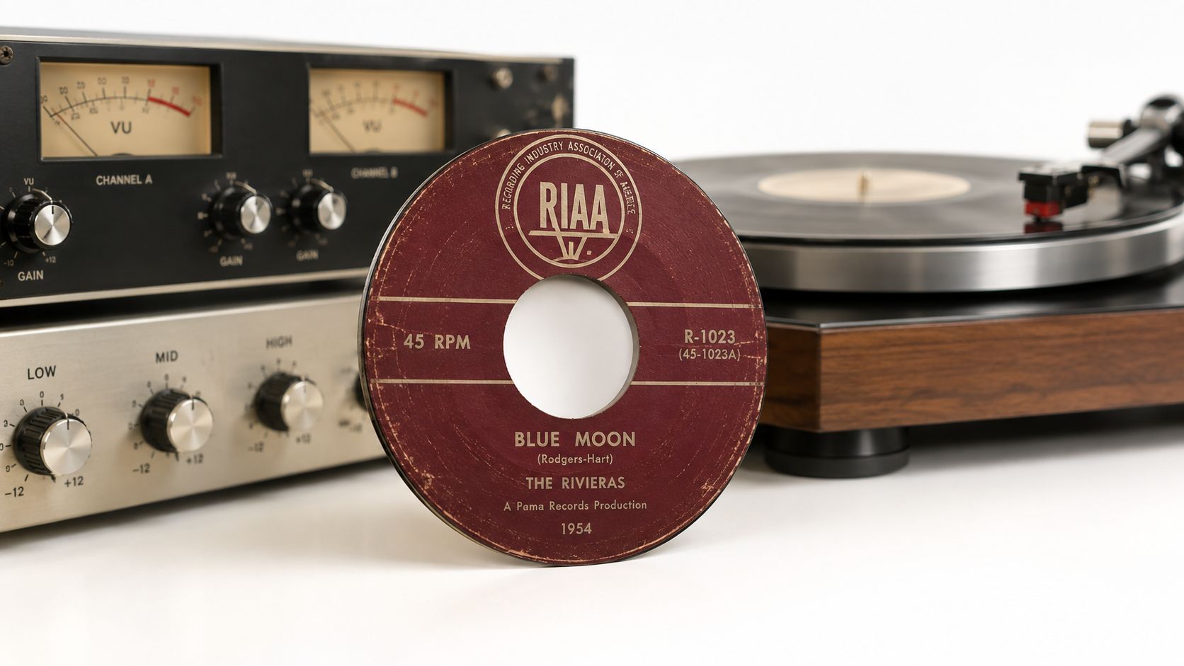 A vintage 45 RPM vinyl record titled Blue Moon by The Rivieras sitting before audio equipment.